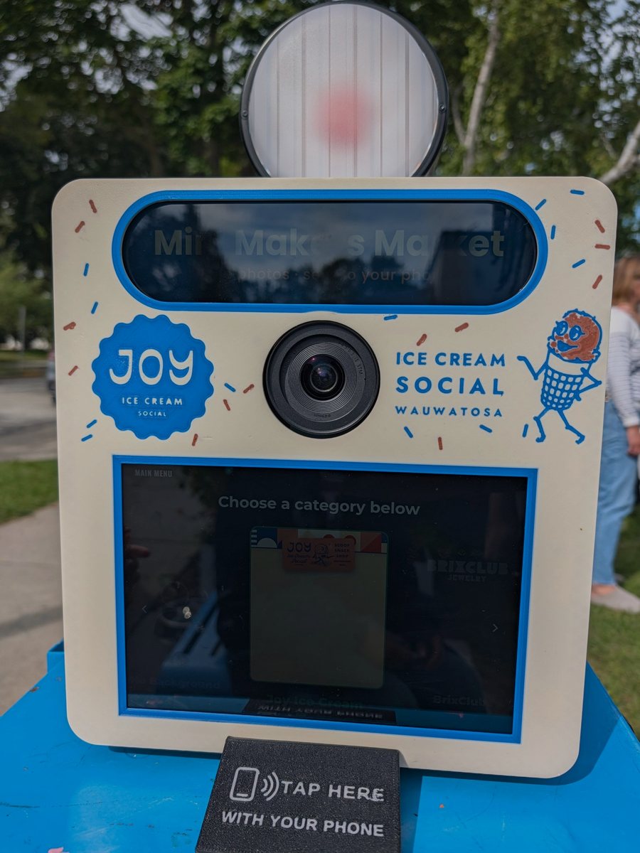 Front of a real Booth dressed for Joy's Ice Cream Social in Wauwatosa: round light on top, billboard screen, camera lens, touchscreen and the tap-your-phone pad