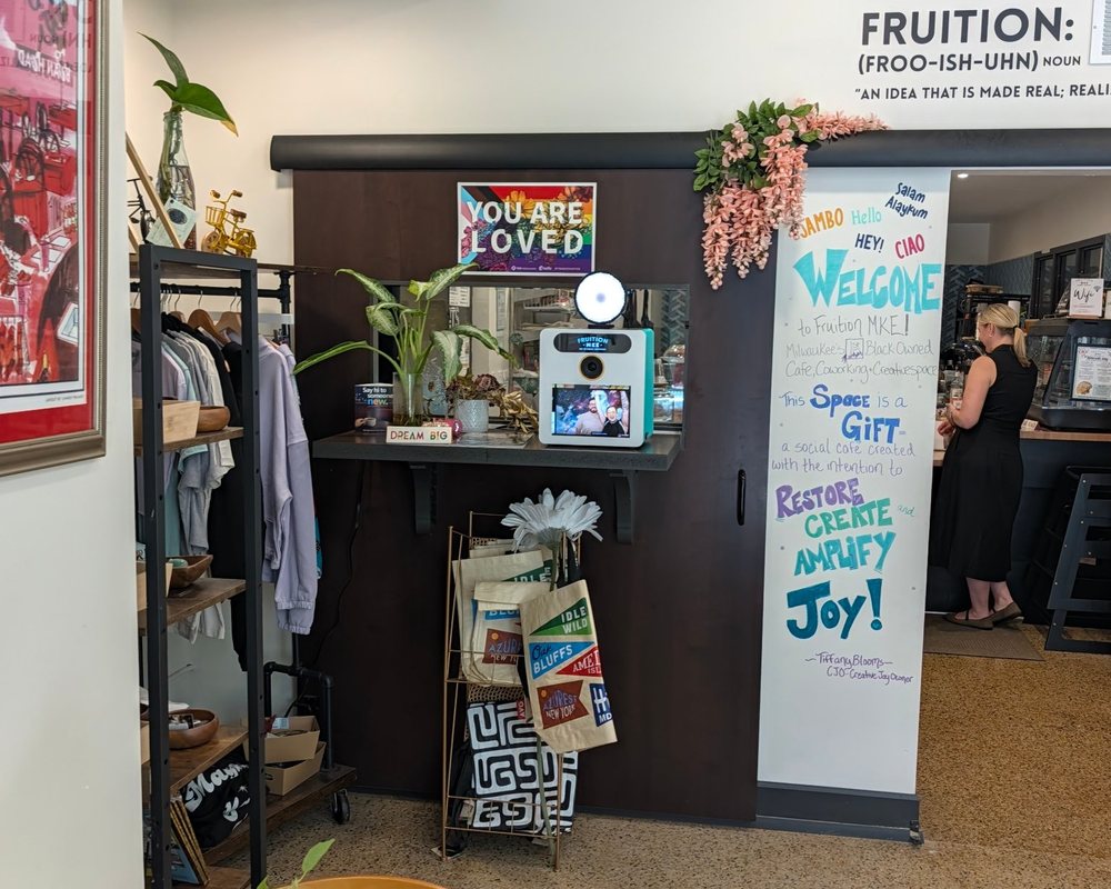 The Booth Mini on its shelf inside Fruition MKE, next to the welcome board